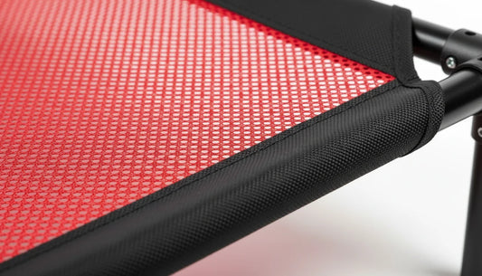 Close-up of red mesh fabric on a black folding chair frame with textured edges and joints
